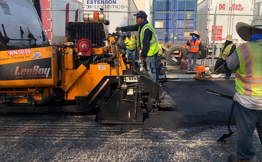 Two men operating paving equipment